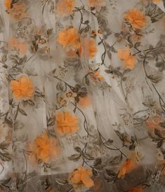 an orange and white flowered sheer fabric with flowers on the bottom half of it