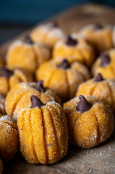 small pumpkin shaped pastries on a wooden cutting board covered in powdered sugar and chocolate chips