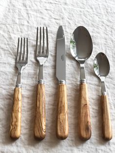 five forks, knives and spoons laid out on a table