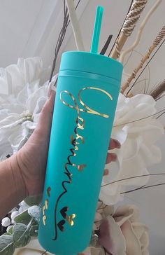 a hand holding a blue tumbler with gold lettering