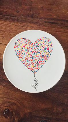 a heart shaped plate with confetti on it and the word love spelled in cursive writing