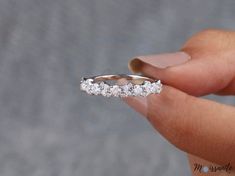 a woman's hand holding a wedding ring with five stones on the inside of it