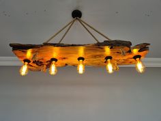 a light fixture made out of wood with lights hanging from the ceiling and bulbs on each end