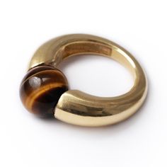 "Tiger Eye Geometric Cocktail Ring. FREE EXPRESS SHIPPING! Your new jewelry direct to your door! The Donut Tiger eye stone ring's benefits are beyond words: it is an incredible stone for achieving clarity. Traditionally carried as a talisman, this tiger ring is hand-forged for those who are glamorous and not afraid to show it. This sweet and colorful piece can also make the perfect birthday gift. If you love this piece with its inspiring tiger eye design, then you'll love our Blue round stone ri Modern Dome Ring With Gemstone, Modern Gold Crystal Ring With Gemstone, Modernist Gold Jewelry With Gemstones, Modernist Gold Gemstone Jewelry, Modernist Oval Gold Rings, Modern Brass Open Ring, Modernist Open Dome Ring As Gift, Modern Yellow Gold Rings, Modern Brown Ring Jewelry