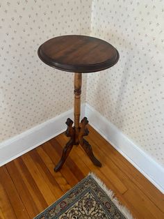 a small wooden table sitting on top of a hard wood floor next to a wall