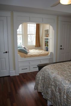 a bedroom with a bed and built in bookshelves on either side of the window