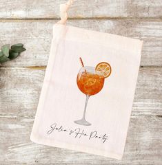 a tea towel with an orange slice and a drink in it on top of a wooden table