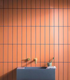 an orange tiled bathroom with two sinks and soap dispenser