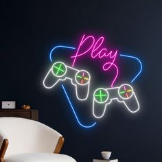 a neon sign that says play with two video game controllers in front of a chair