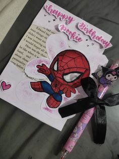 a spiderman birthday card and pen on a bed