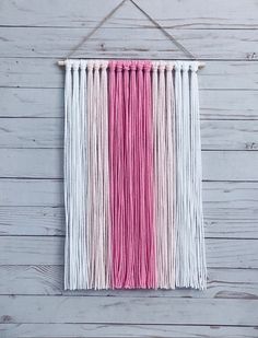 a pink and white wall hanging on a wooden wall