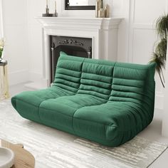 a green futon sofa sitting in front of a fireplace