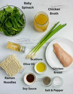 ingredients to make chicken broth laid out on a white table with green onions, sesame seeds, baby spinach, oil, salt and pepper