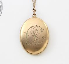 "A fantastic large-sized antique yellow gold-filled locket with a bloomed finish and applied Etruscan style wire-work filigree decoration. The filigree pattern is reminiscent of a William Morris print with its gracefully exuberant arrangement of scrolls framing the stone. The back has been engraved with the initials \"C.L.\" in rich foliate ribbon script. Measuring approximately locket 1 5/8\" inches north to south and 1 1/4\" east to west; the locket opens to reveal a gilded interior with space Elegant Gold Filigree Locket Necklace, Antique Gold Filigree Jewelry For Anniversary, Victorian Filigree Medallion Jewelry, Victorian Locket Necklace With Intricate Design For Formal Occasions, Victorian Locket Necklace With Intricate Design For Formal Events, Ornate Yellow Gold Hallmarked Locket Necklace, Antique Gold Filigree Classic Jewelry, Antique Gold Classic Filigree Jewelry, Ornate Yellow Gold Medallion Locket Necklace