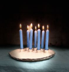 five blue candles are lit on a plate