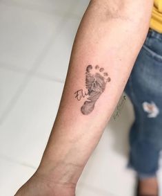 a person with a tattoo on their arm holding a baby's hand and foot