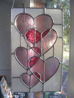 a stained glass window with hearts hanging from it's sides, in the shape of a heart