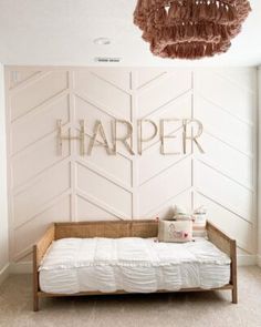 a bedroom with a bed, chandelier and wooden letters that spell out harper