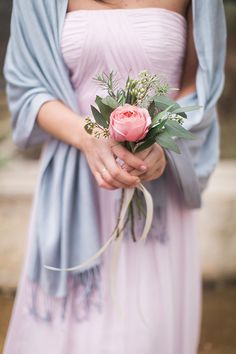 a woman in a dress holding a pink rose