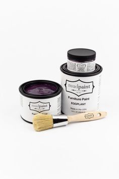 a paint can and brush sitting next to each other on a white surface with a black lid