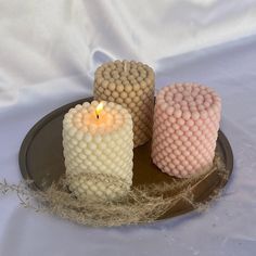 three candles are sitting on a plate with some string