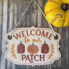 a welcome to our patch sign hanging on a wooden wall with pumpkins and gourds