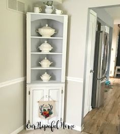 a white china cabinet sitting in the corner of a room