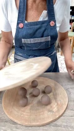 a person in overalls and an apron holding a surfboard on top of a wooden table