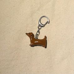 a brown dachshund keychain sitting on top of a white cloth