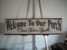 a sign that says welcome to our porch one sit at a spell on a stand