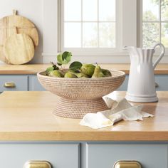 a bowl filled with fruit sitting on top of a kitchen counter