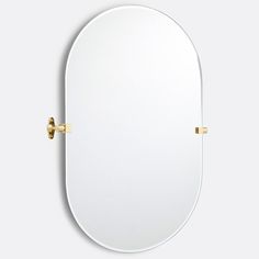 an oval mirror with brass fittings on the front and back, against a white background