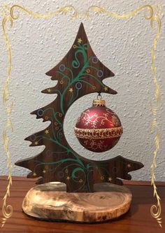 an ornament with a christmas tree on it is sitting on a wooden table