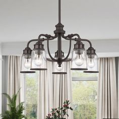 a chandelier hanging from a ceiling in a dining room with windows and curtains