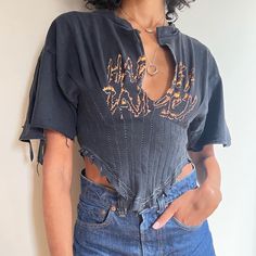 a woman with short black hair wearing a blue shirt and jeans is posing for the camera