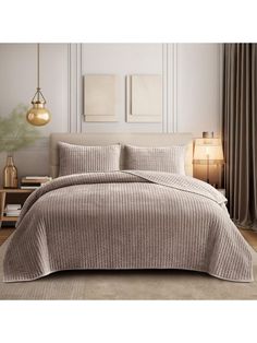 an image of a bedroom setting with comforter and bedding in grey tones,