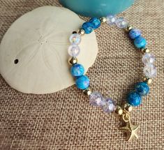 Elegant 7-inch bracelet made to fit most adult women.  Delicate golden starfish charm hangs from turquoise blue and iridescent bracelet. Beaded Stretch Bracelet, Stretch Bracelet, Turquoise Blue, Stretch Bracelets, Starfish, Bracelet Making, Jewelry Bracelets, Bathing Beauties, Accessory Gift