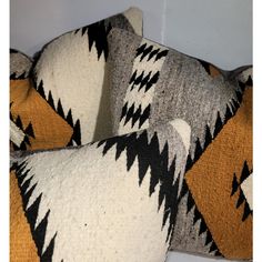 two decorative pillows with black and orange designs on them, one is made out of wool