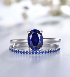 a ring with a blue stone on the side and white diamonds around it, sitting on top of a table