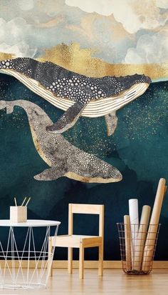 two whales swimming in the ocean under a cloudy sky wallpapered with gold and blue paint