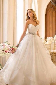 a woman in a white wedding dress is posing for the camera