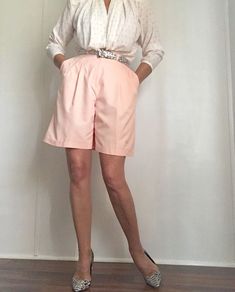 "Super feminine Vintage 80s Bermuda Shorts in the most lovely peach tone. These highwaisted shorts feature a pleated front, wide flared legs, two deep side pockets and loop holes for your favorite belt. Front zipper and button closure. One back pocket. Extremely comfortable yet stylish and very classy. Perfect for even the hottest of days. Match with your favorite vintage blazer or/ and top, creating the ultimate 80s fashion style. Polyester Best fits Size m-l depending on desired drape. Tag rea Feminine High-waist Fitted Shorts, Feminine Fitted High Waist Shorts, Feminine Fitted High-waist Shorts, Pink High-waisted Bermuda Shorts For Spring, High Waist Peach Bottoms For Spring, Spring High Waist Bermuda Shorts With Elastic Band, Spring High Waist Bermuda Shorts With Elastic Waistband, High-waist Peach Bottoms For Spring, Summer Bermuda High-waisted Shorts For Daywear