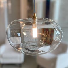 a clear glass light fixture hanging from a ceiling in a living room or dining room