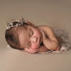 a newborn baby wearing a tiara sleeping