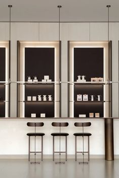 a counter with four stools in front of it and several shelves on the wall