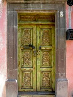 an old wooden door is shown in front of a pink building with ornate carvings on it