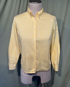 This is a charming vintage blouse from the 1960s or early 70s. No labels or tags. The bust measures 38". Please see measurements below.  Made of yellow and white gingham check cotton. It has long sleeves with button cuffs. The neckline is collared with a button-down collar.  Buttons down the front with plastic buttons. Hemline is straight. It has solid yellow elbow patches.  The blouse is in good, vintage condition.  Super cute! If you have never worn vintage before, please measure yourself!! Vintage sizes run smaller than today's sizes, know your measurements before buying! Bust measured from side seam to side seam at the underarm: 19" for a 38" or smaller bust  Waist measured from side seam to side seam at hem line: 18.5" for a 36" or smaller waist Shoulders: 14.5" Sleeve from underarm: Classic Yellow Blouse For Spring, Vintage Gingham Blouse For Spring, Classic Gingham Cotton Blouse, Classic Yellow Blouse With Button Closure, Spring Vintage Gingham Blouse, Retro Gingham Tops With Button Closure, Retro Gingham Blouse For Spring, Retro Gingham Top With Button Closure, Classic Yellow Cotton Blouse