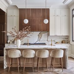 a kitchen with marble counter tops and white chairs in front of an island surrounded by wooden cabinets