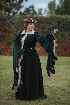 A classical houppelande: majestic outer garment from the far 15th century made of deep emerald velvet. Flared sleeves, collar, and voluminous skirt - everything in it is showing off an original Middle Ages flavor. The outfit is accomplished with a belt and a lacing edged with beads on the front side. The headdress and underdress aren't included in the costume. But you can order the underdress in our store. Houppelande would become your best look for Middle Ages historical events or LARP, fantasy Fall Medieval Dress Costume With Historical Design, Long Sleeve Medieval Dress For Costume Party, Medieval Dress For Fantasy Events In Fall, Long Sleeve Velvet Outerwear For Costume, Long Sleeve Medieval Dress For Costume Party In Fall, Long Sleeve Medieval Dress With Historical Design For Festivals, Long Sleeve Medieval Dress With Historical Design For Fall, Elvish Long Sleeve Medieval Dress For Costume Party, Elegant Long Sleeve Medieval Dress For Festivals