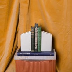 two books are stacked on top of each other in front of a yellow background with a gold curtain